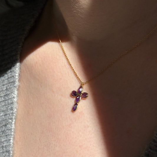 Detalle de la cruz de amatista del Collar Amara iluminada por el sol