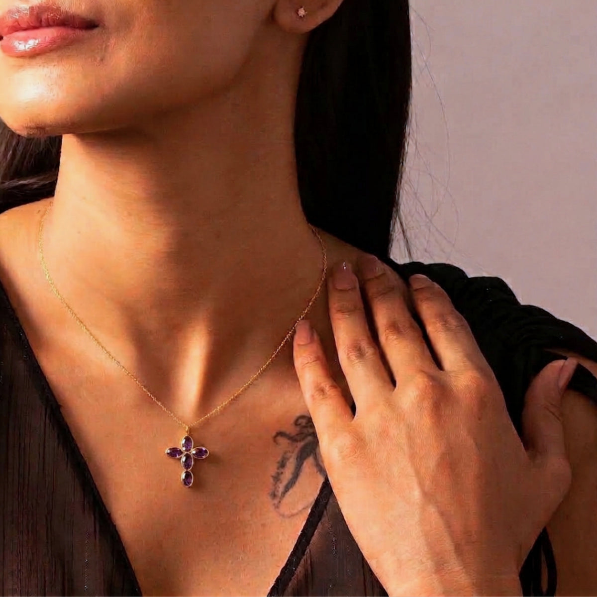 Mujer con el Collar Amara de cruz de amatista y la mano sobre el pecho