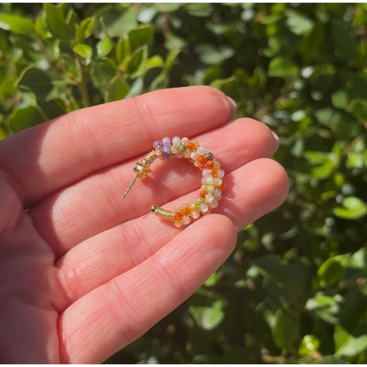 Pendiente Lunara sostenido en la mano, con sus minerales de colores al aire libre