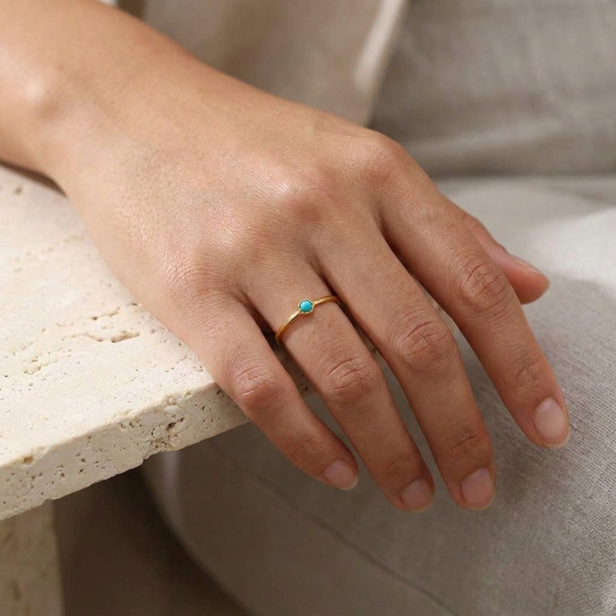 Mano apoyada sobre piedra clara con el Anillo Aura de turquesa puesto