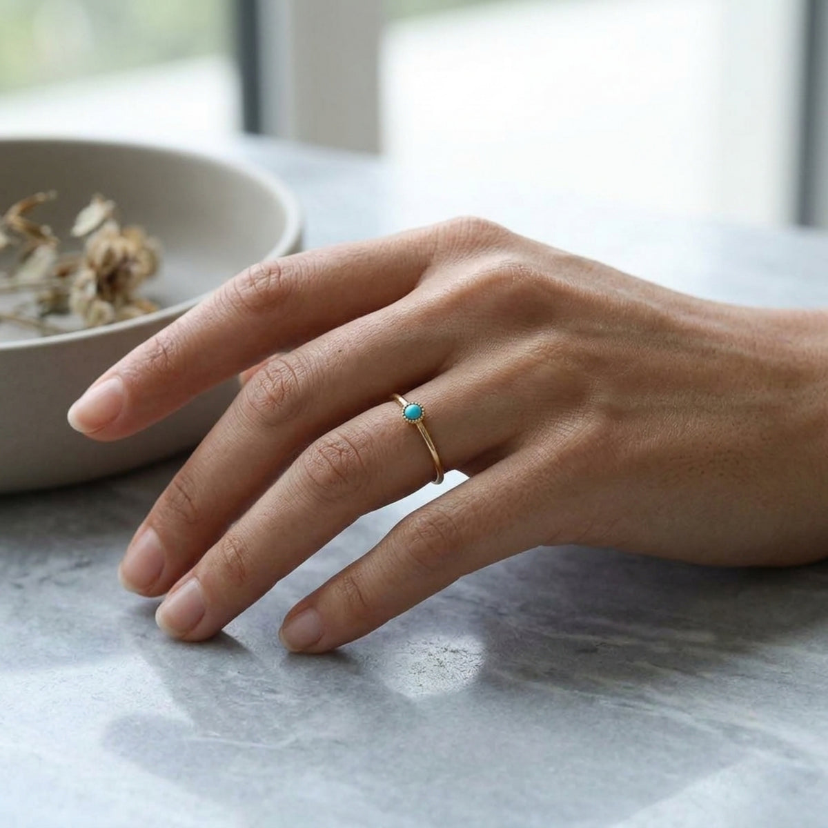 Anillo Aura de turquesa visto de cerca en la mano, sobre una mesa de piedra