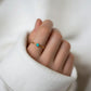 Mano cerrada con el Anillo Aura de turquesa asomando por la manga de un jersey blanco