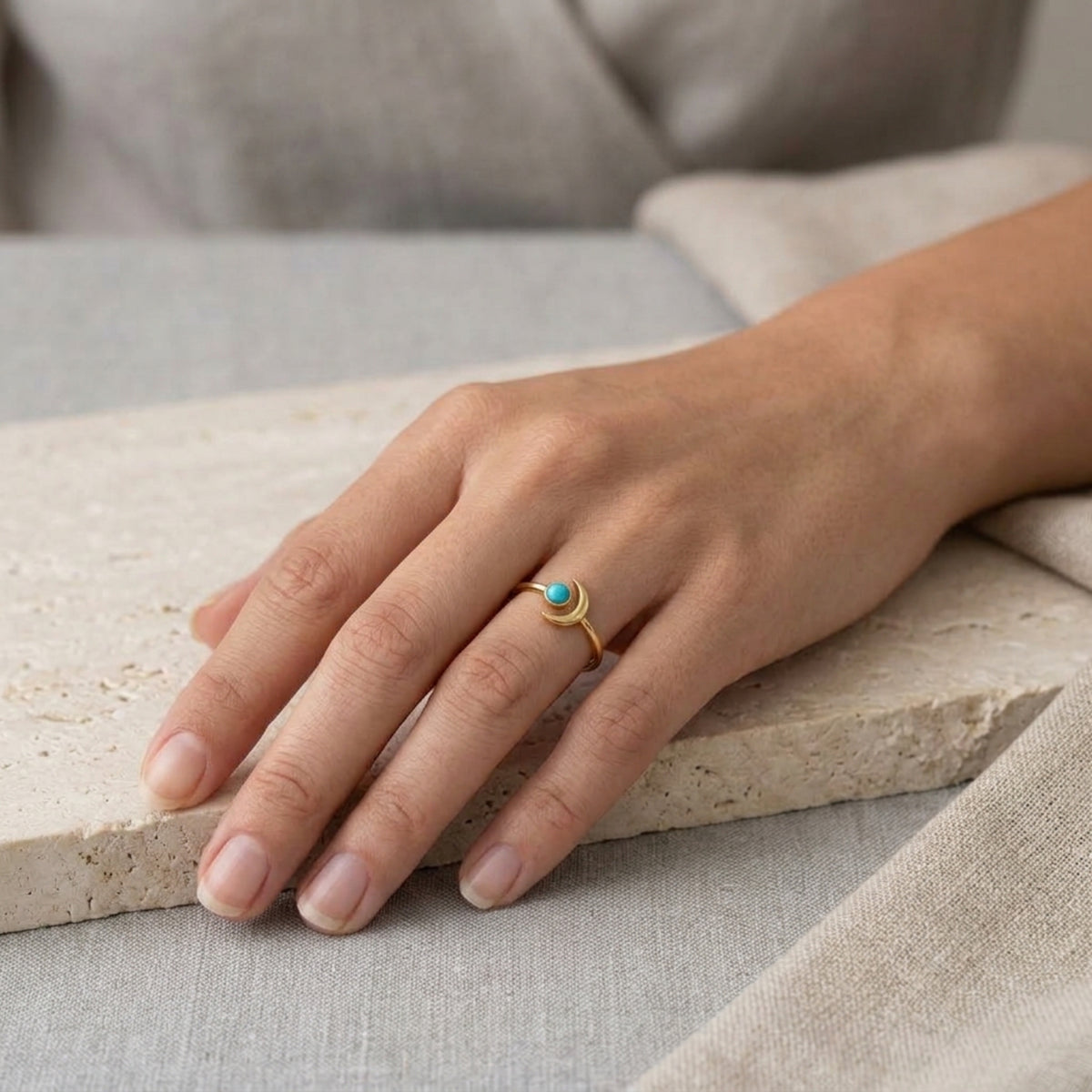 Mano en reposo sobre lino con el Anillo Aylin de luna y turquesa puesto