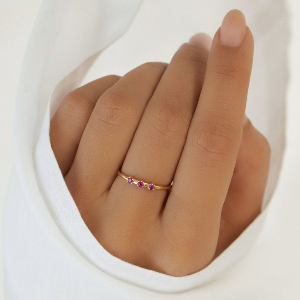 Mano sobre tela blanca con el Anillo Nara puesto y su fila de amatistas