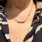 Collar Mamá en acabado plateado puesto, con la palabra MAMÁ y el corazón rojo