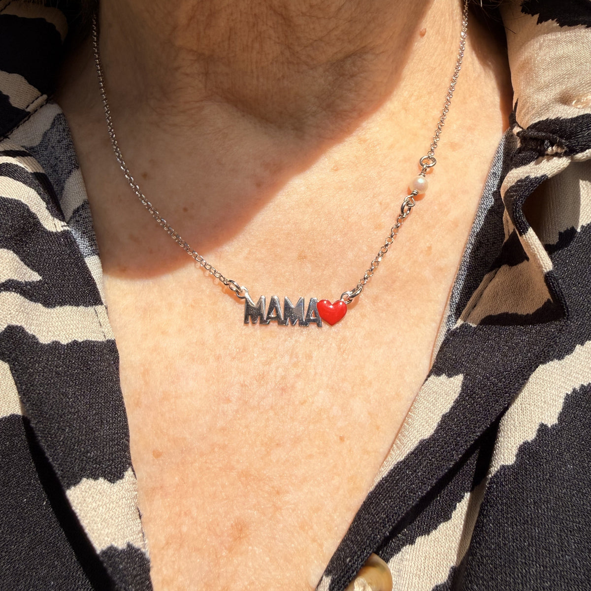 Collar Mamá en acabado plateado puesto, con la palabra MAMÁ y el corazón rojo