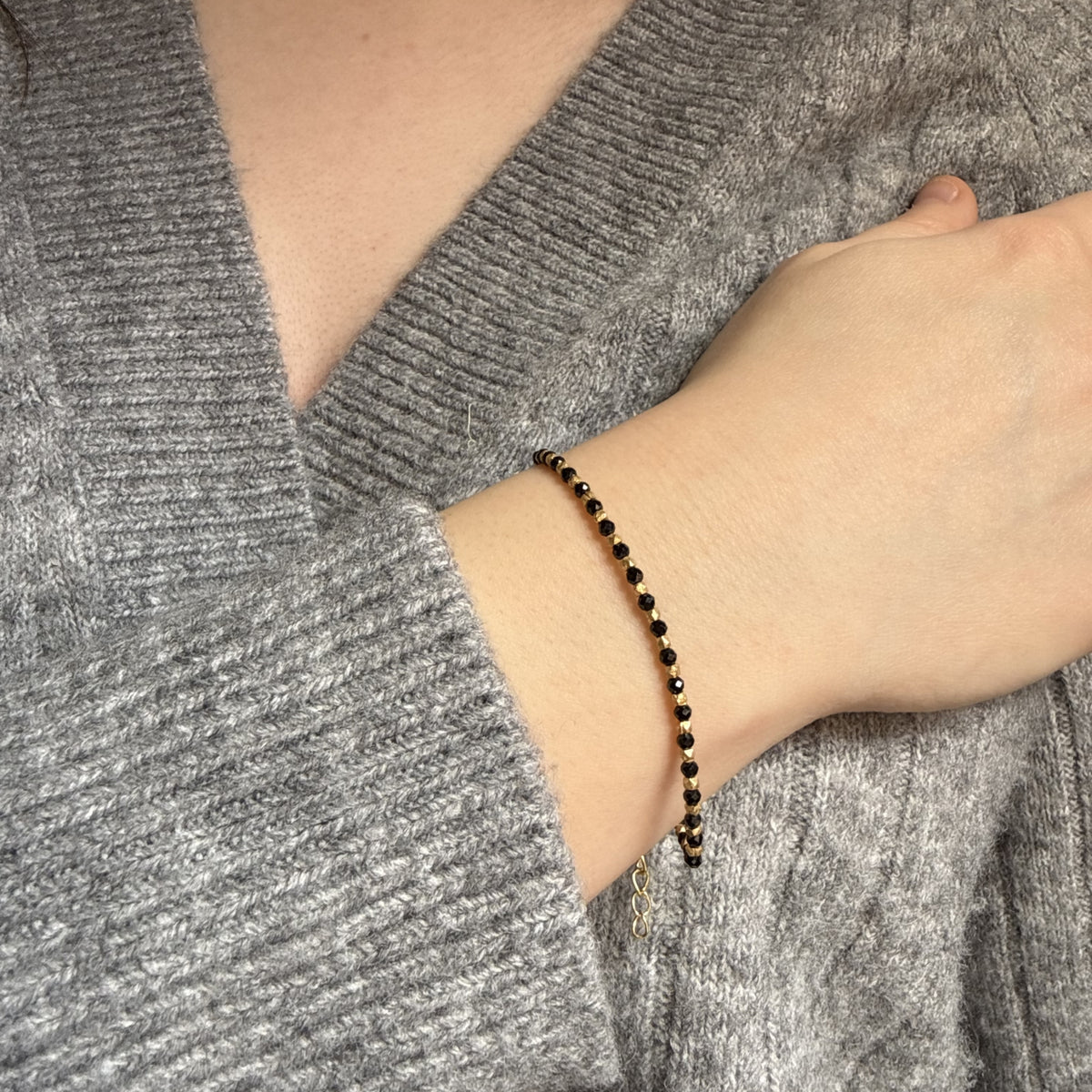 Pulsera Astra de ónix negro puesta sobre un jersey gris