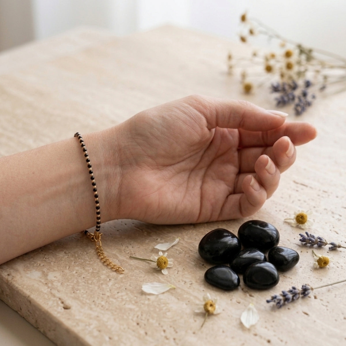 Pulsera Astra en la muñeca junto a varias piedras de ónix negro